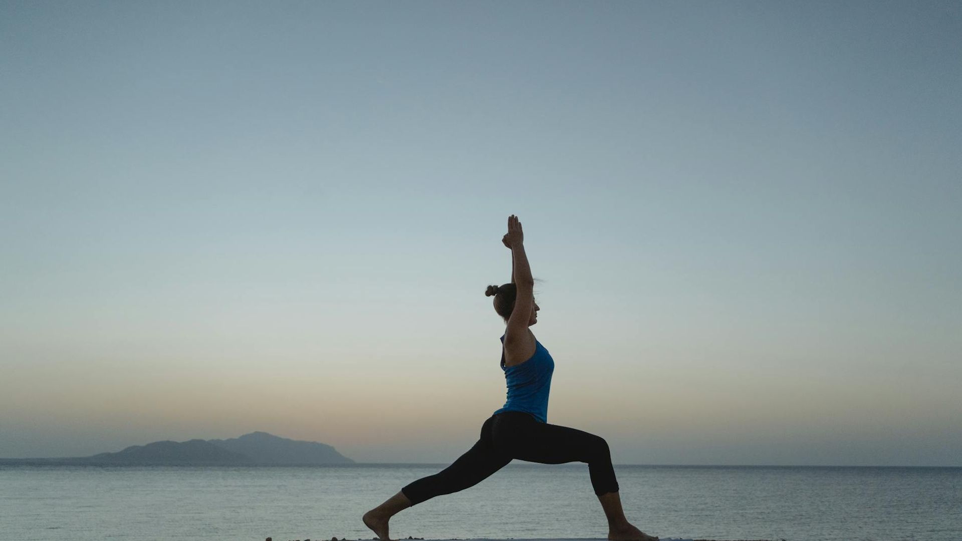 Silhouette of a woman in a calm yoga pose at sunrise.